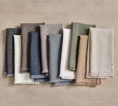 various muted fall color napkins splayed w=out on a tan background
