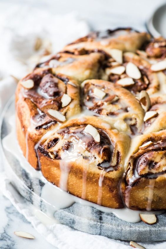 a plate of cinnamon rolls dripping with powdered sugar glaze