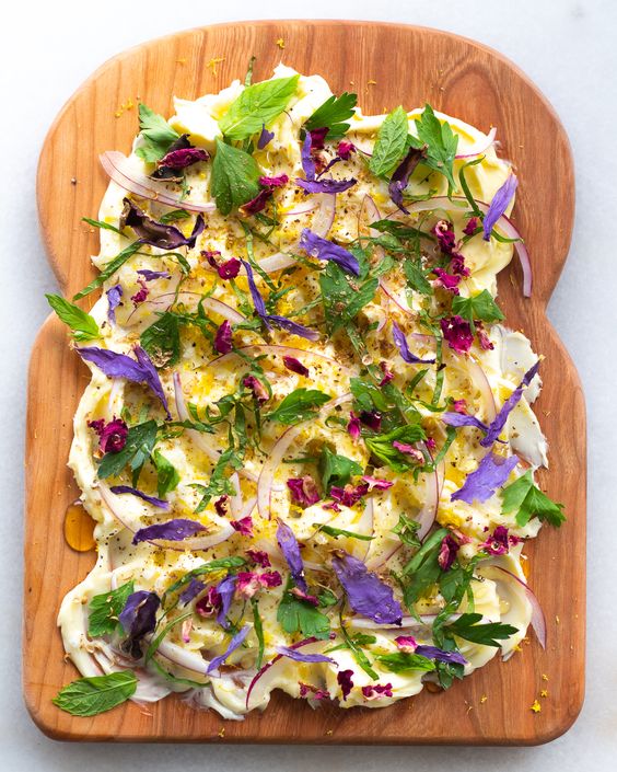 bread shaped wood board slathered in butter with herbs