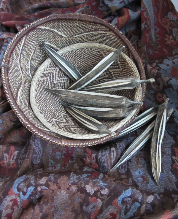 dried okra in African baskets on a vintage scarf