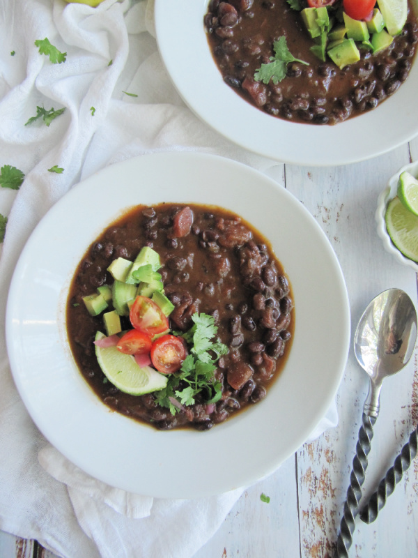 easy slow cooker black bean soup in a white bowl with 2 spoons