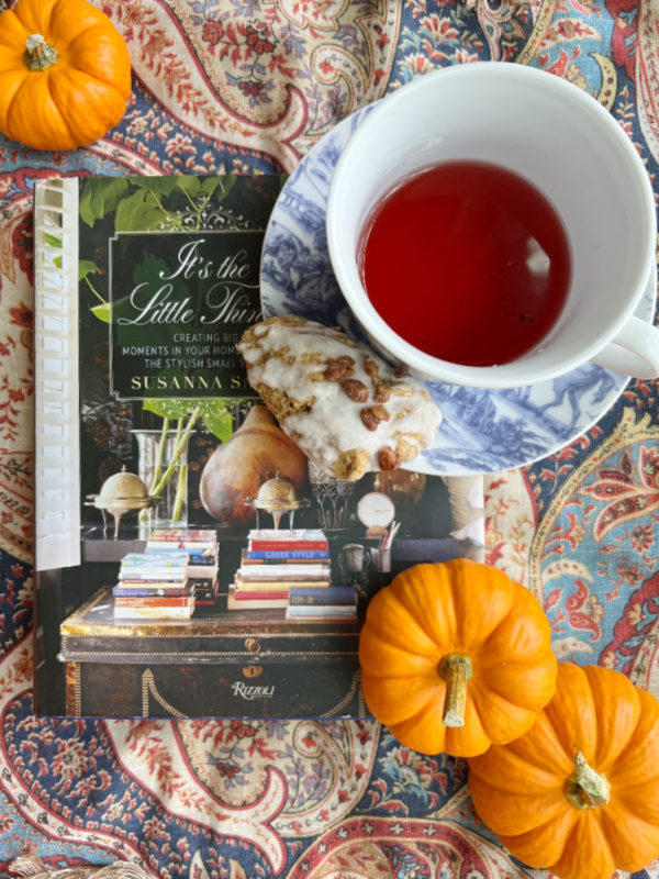 flatlay with toile tea cup orange pumpkins and Susanna Salk book its the little things on a paisley background
