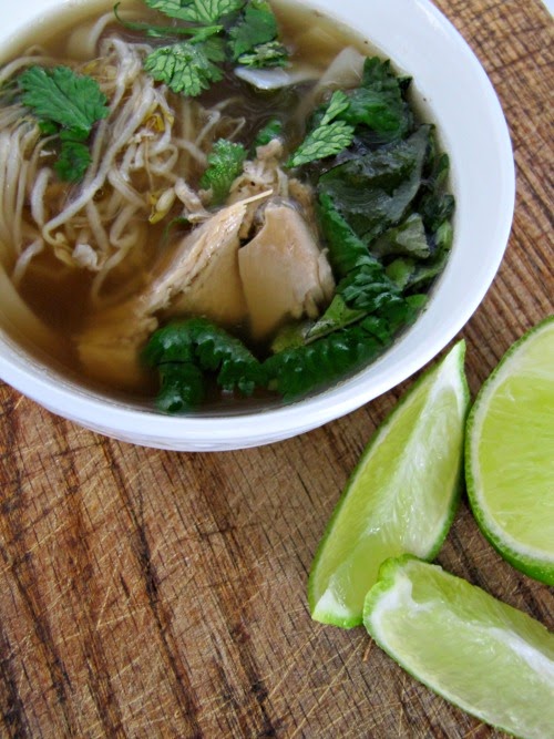 pho-soup with limes in a white bowl on a brown cutting board