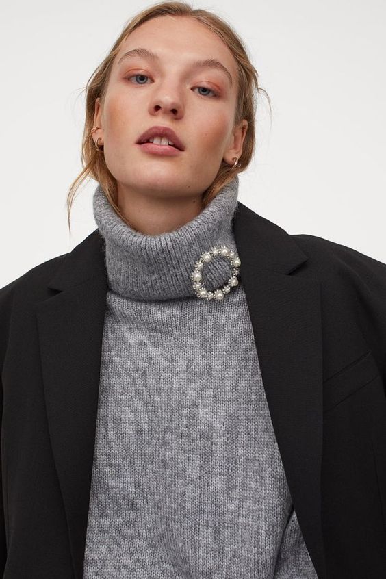 Girl wearing a great turtleneck sweater and a black blazer with a circle brooch