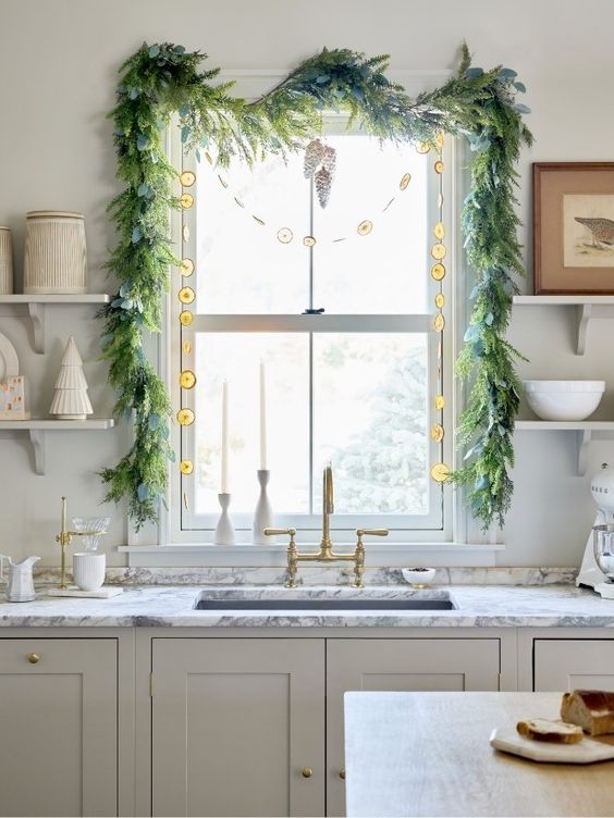 view of a white kitchen with a window over the sink decorated with christmas garland