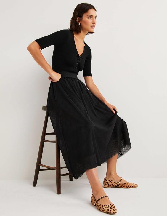 woman leaning on a chair wearing a black tulle skirt and black sweater.