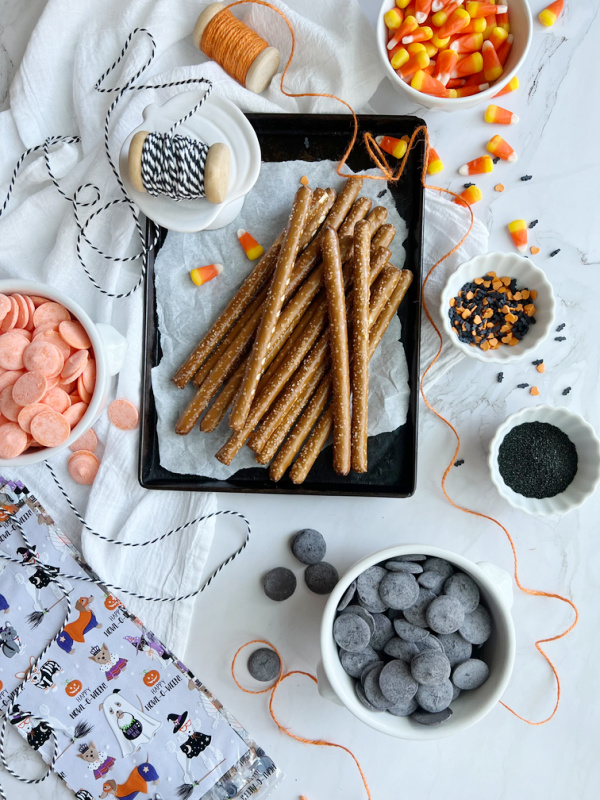 ingredients for chocolate covered halloween pretzels including pretzels black melting wafers and orange melting wafers.
