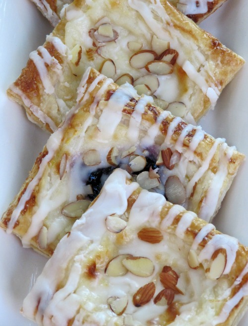White platter with 4 cream cheese and fruit pastries.