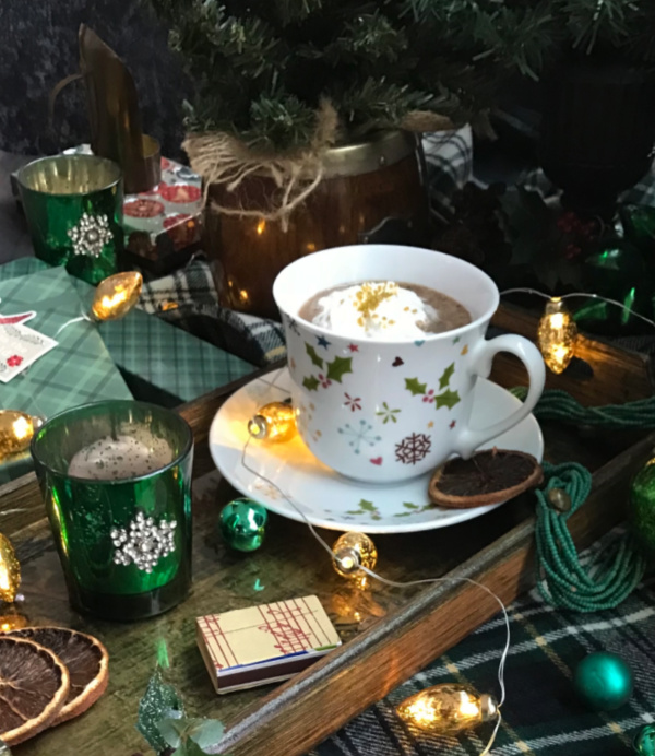 weekend meanderings hot chocolate on tray laying on plaid blanket with christmas lights and bulbs