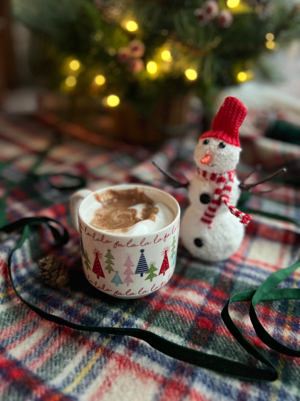 hot chocolate in a cup with fa la la la la and a snowman
