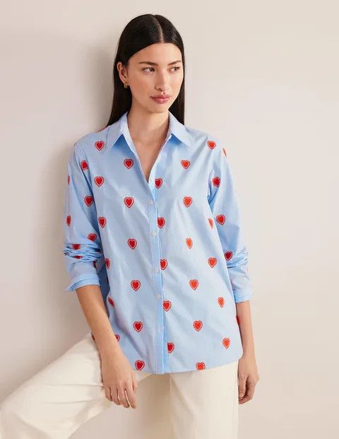 woman wearing a blue and white shirt with embroidered hearts. 