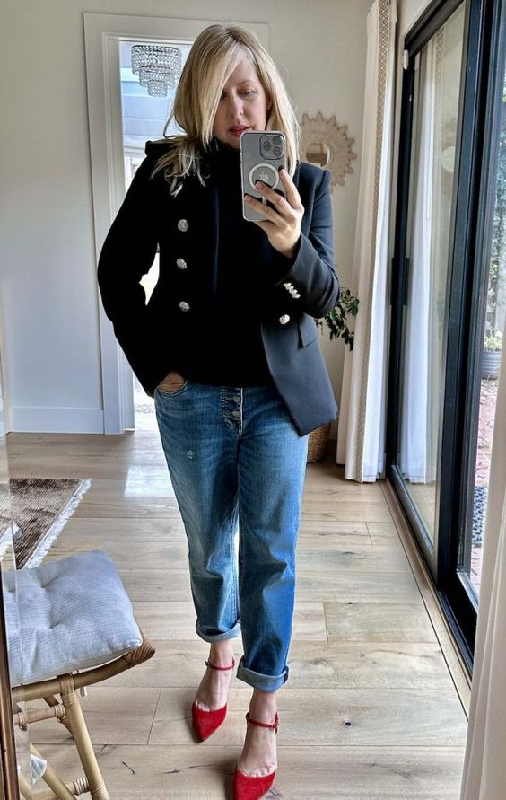 Woman wearing red shoes, jeans and a black blazer.