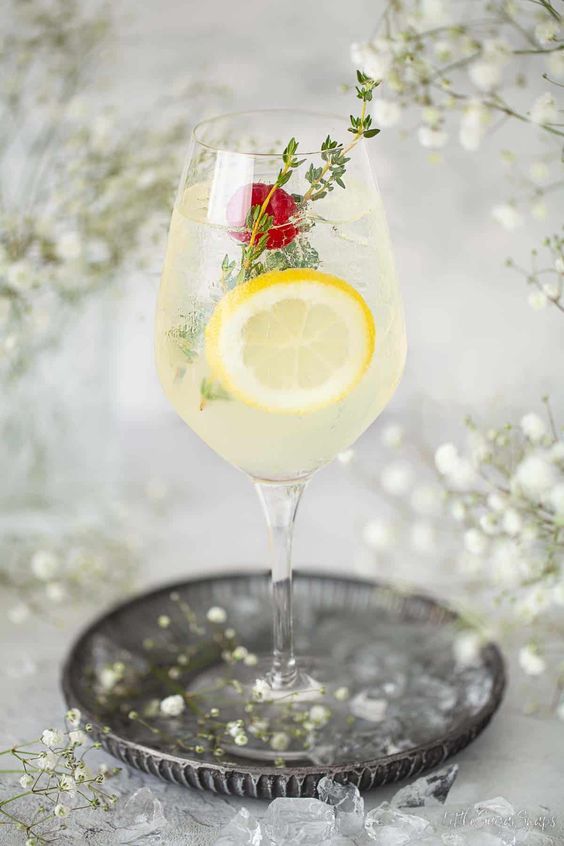 LIMONCELLO SPRITZ in a wine glass sitting on a silver tray. 
