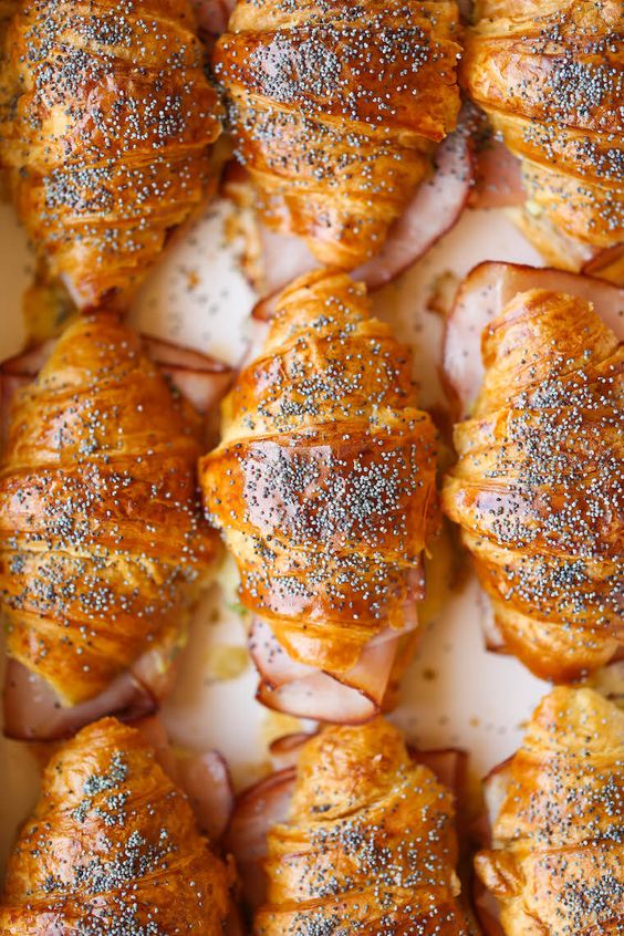 Baked ham and cheese croissants in a white pan.