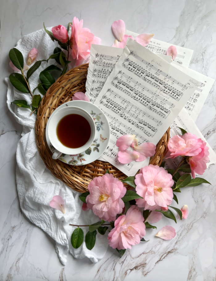 Friday Favorites Flatlay early spring with camellia flowers cup of tea and sheet music.