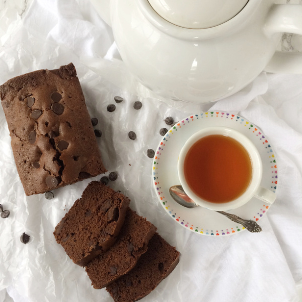 Ina Garten chocolate loaf cake with a cup of tea and a white tea pot.