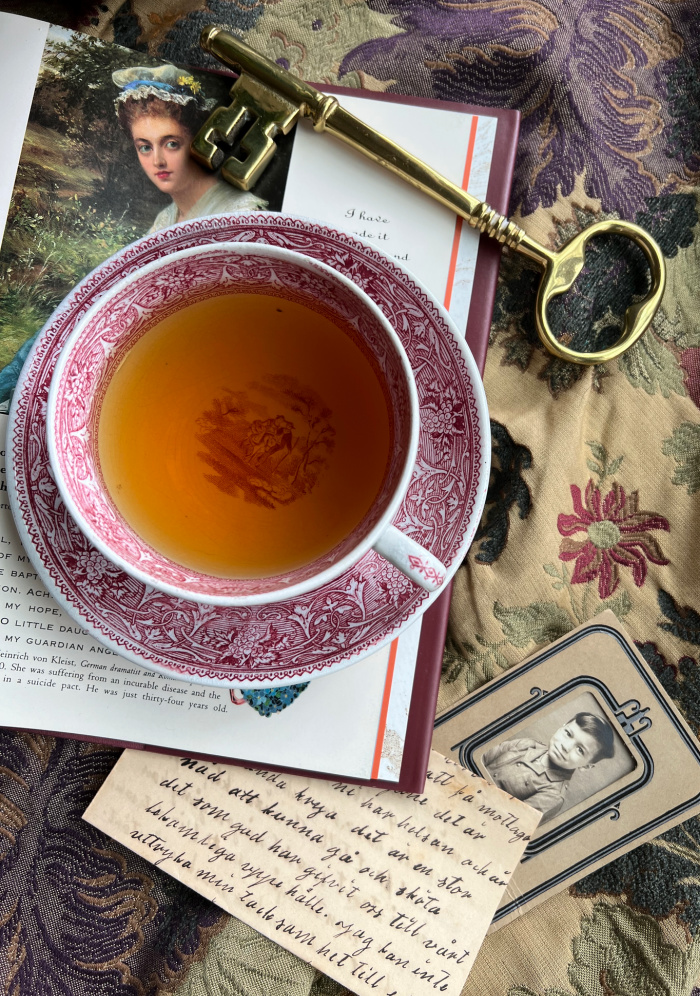 flatlay with book tea brass key photo of little boy and old letters on brocade