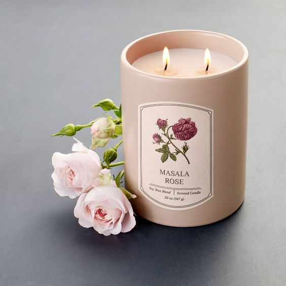 Rose candle in a jar with roses next to it. 
