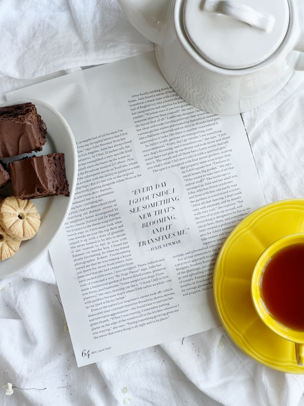Flatlay with magazine article, plate of cookies and brownies and a cup of tea.