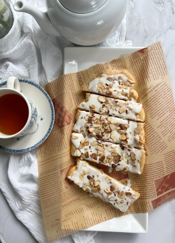 almond kringle danish puff pastry on a white platter with a cup of tea
