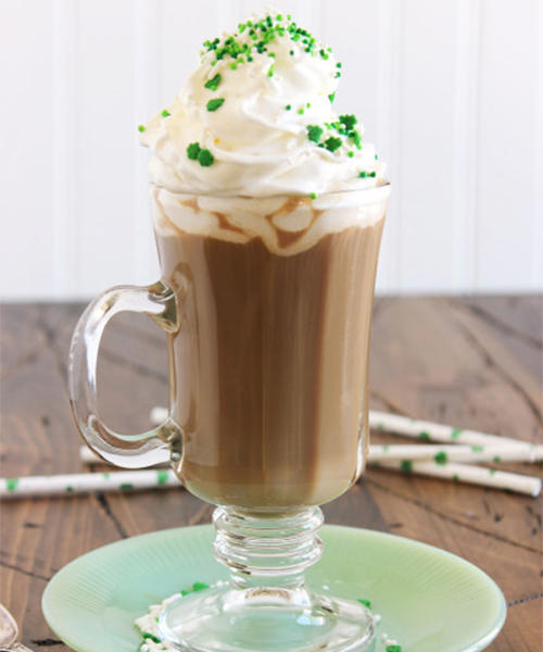 Irish coffee drink with lots of whipped cream and green sprinkles.