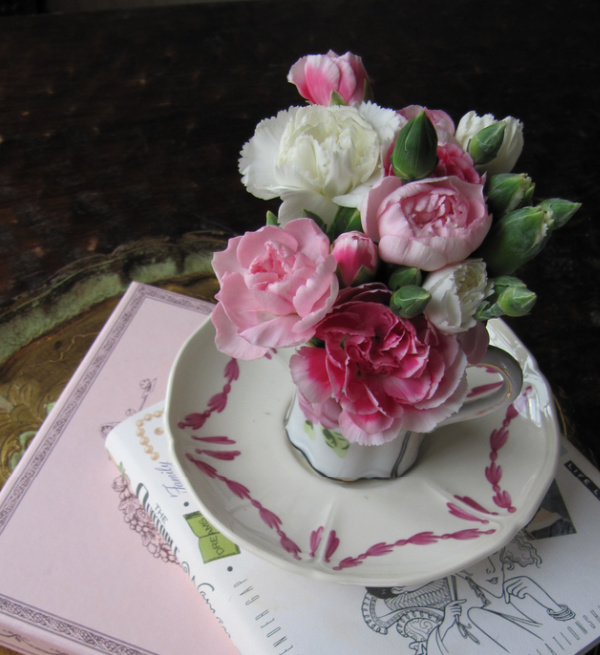Friday Favorites pink flowers in a tea cup on a pile of pink and white books.