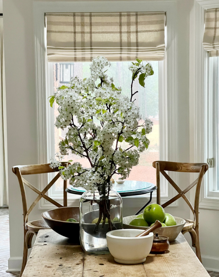 spring branches in a glass jar on a weathered kitchen island.