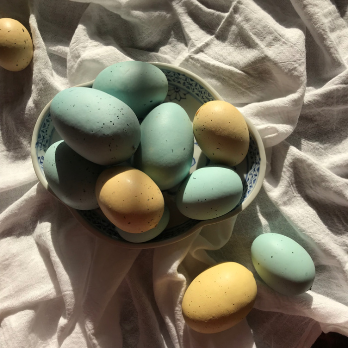 blue and yellow eggs in a bowl on a white cloth