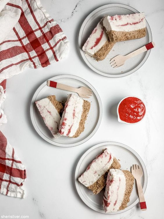 Ice cream bars on 3 plates with a small bowl of raspberry puree. 