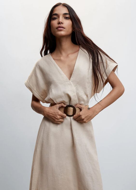 Woman wearing a tan linen belted dress. 
