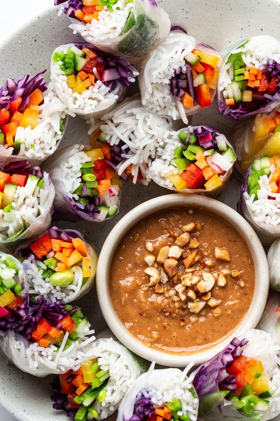Pad Thai summer rolls with a bowl of peanut sauce.