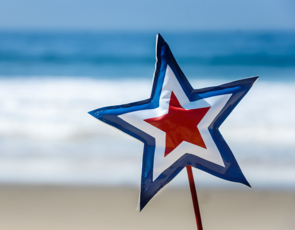 red white and blue paper star on a stick stuck in the sand.