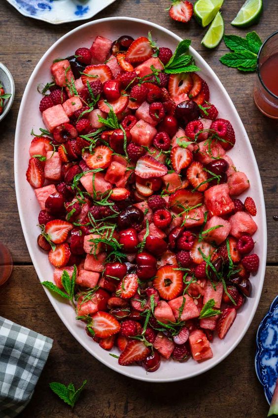 A large white oval platter piled high with a watermelon berry salad.