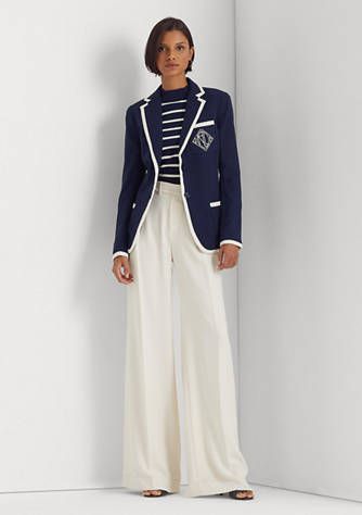 Woman wearing white pants, blue and white stripe shirt and a navy blue blazer with white piping. 