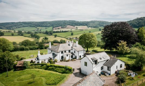 a whitewashed house and barn in rolling green hills.