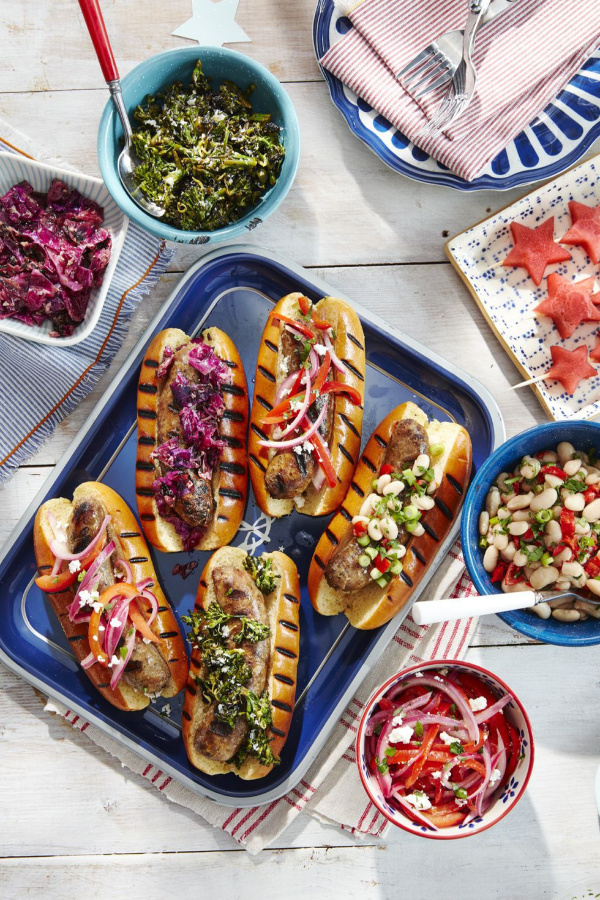 sausages and hot dogs on a platter with all of the fixings.