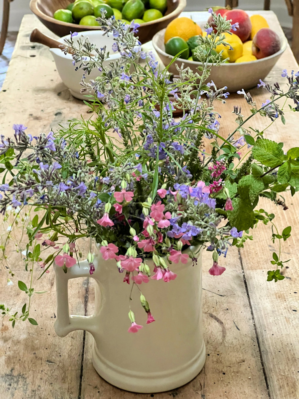 wildflowers in an ironstone pitcher with a bowl of fruit.