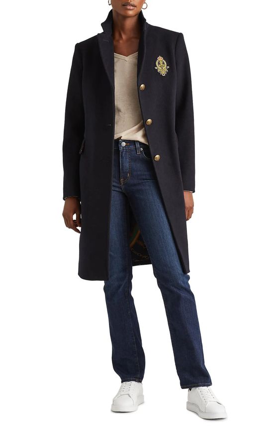 Woman wearing a blue coat with crest. 