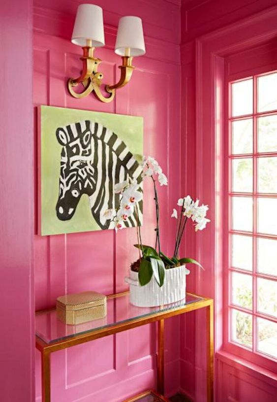 a pink lacquer foyer with a zebra painting and an orchid on a gold table.