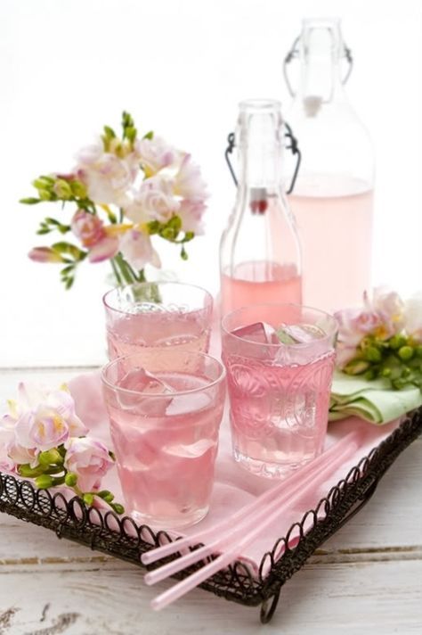 pink lemonade in glasses and bottles with flowers.