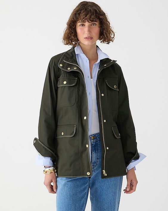 Woman wearing jeans, blue shirt and a green wax jacket. 