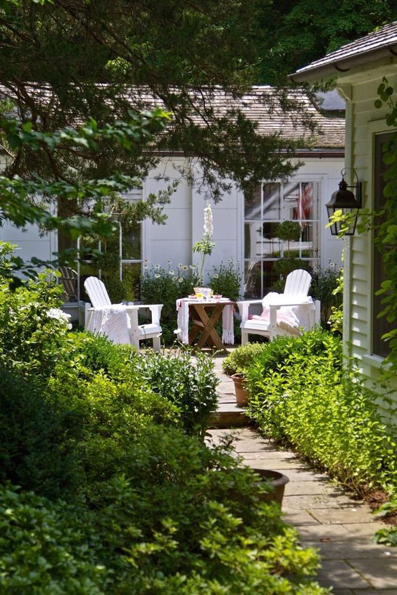 Two white wicker chairs in a garden.