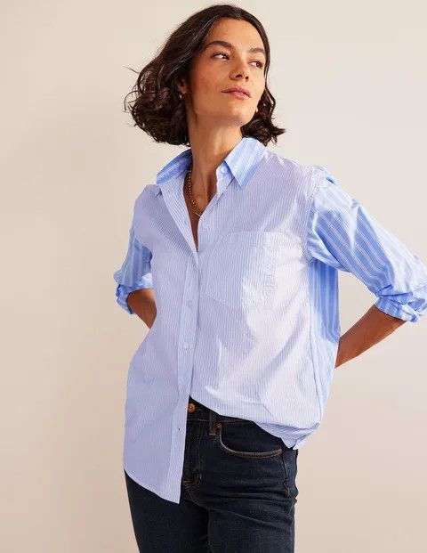A woman with a bob haircut wearing jeans and a blue shirt.
