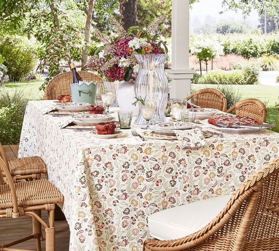 table out on a covered porch set with tan linen and colorful plates. 