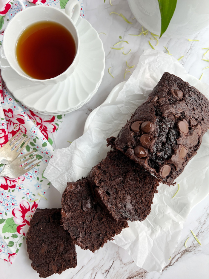 Zucchini Bread sliced on a plate with a cup of tea. 