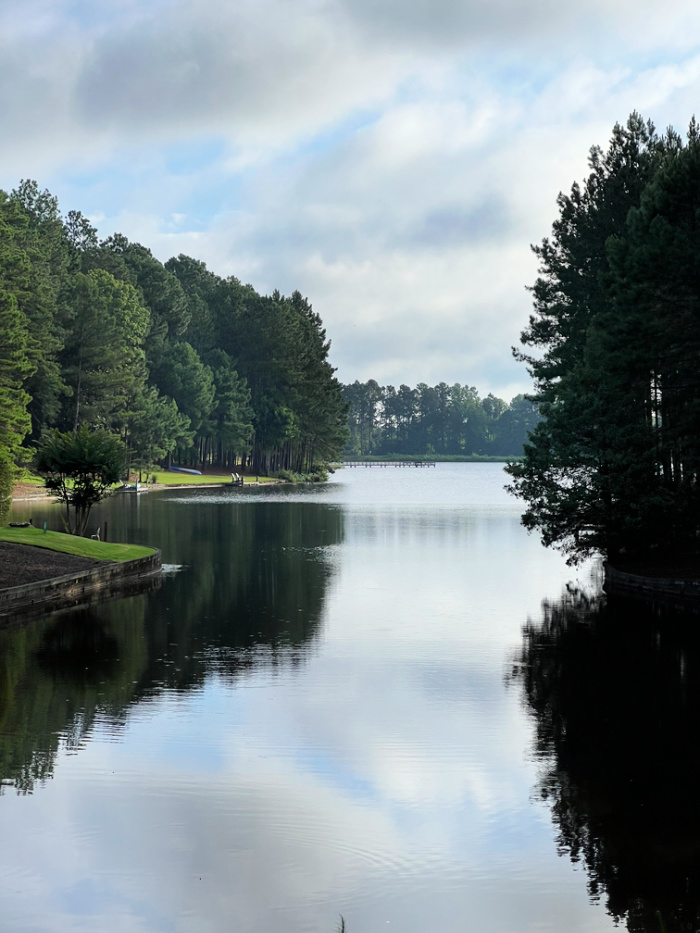 A lake with pine trees on both sides reflecting in the water.