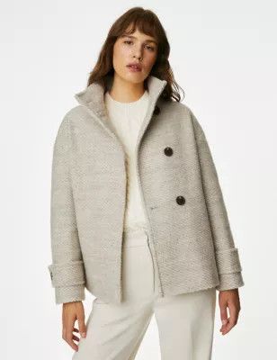 A woman wearing a white shirt and pants with a gray coat. 