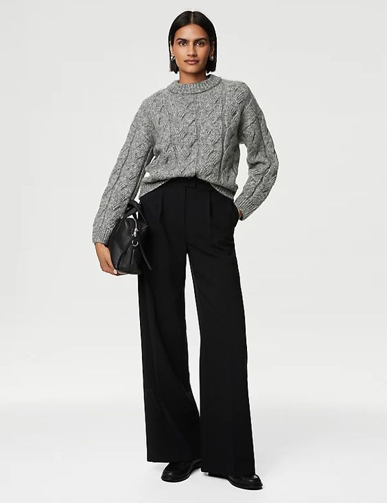 Woman wearing black pants and a gray sweater. 