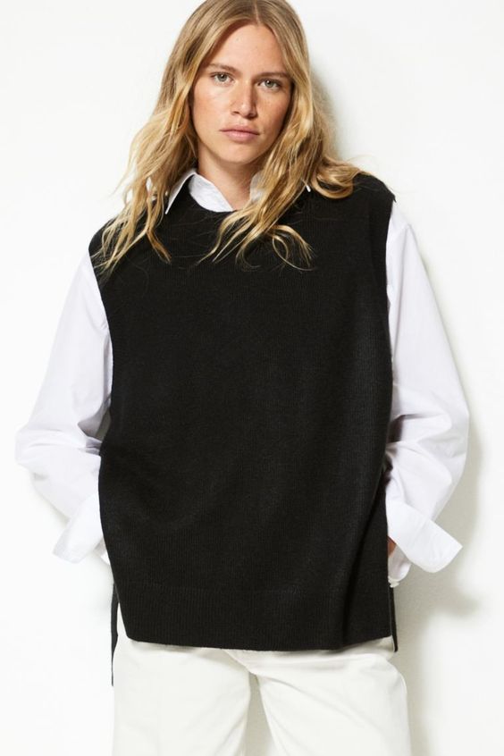 Woman wearing a white shirt, black sweater vest and pants,