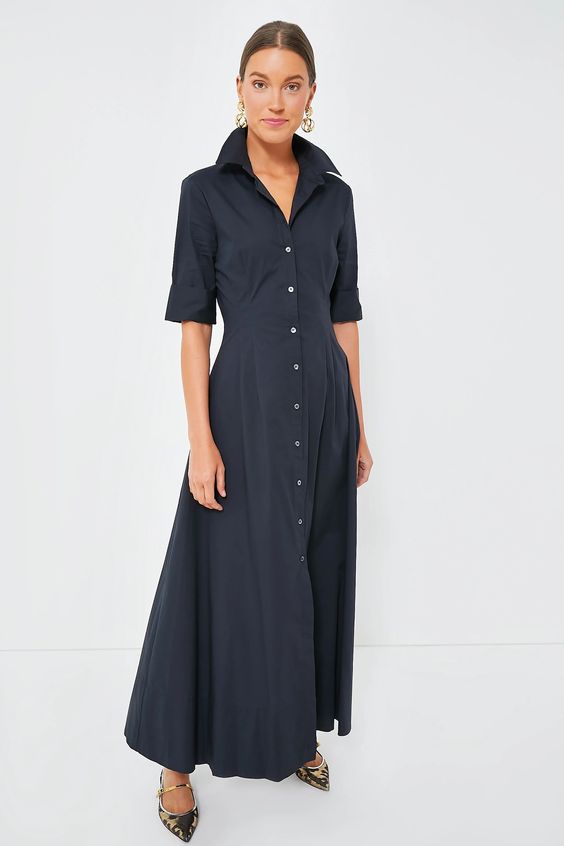 A woman with her hair pulled back wearing a blue shirt dress with the color up. 